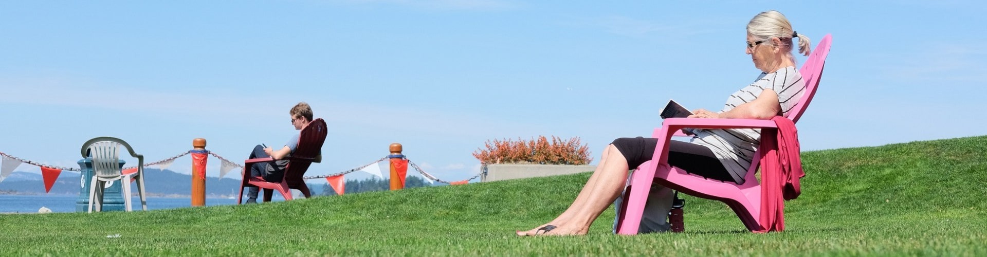 senior woman reading a book as she overlooks a lake